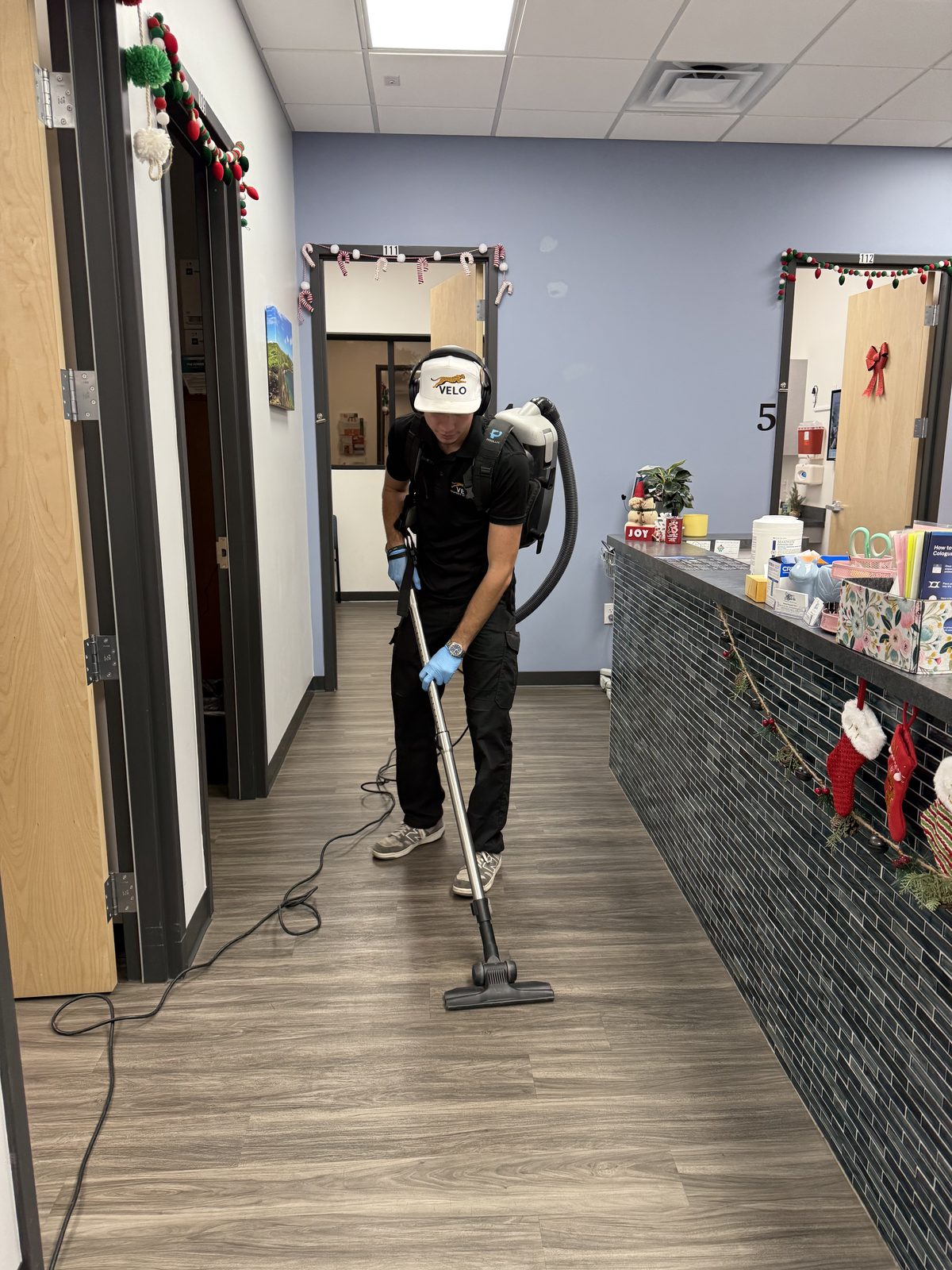 Velo Property Solutions owner Damien in branded uniform performing janitorial cleaning at a medical office