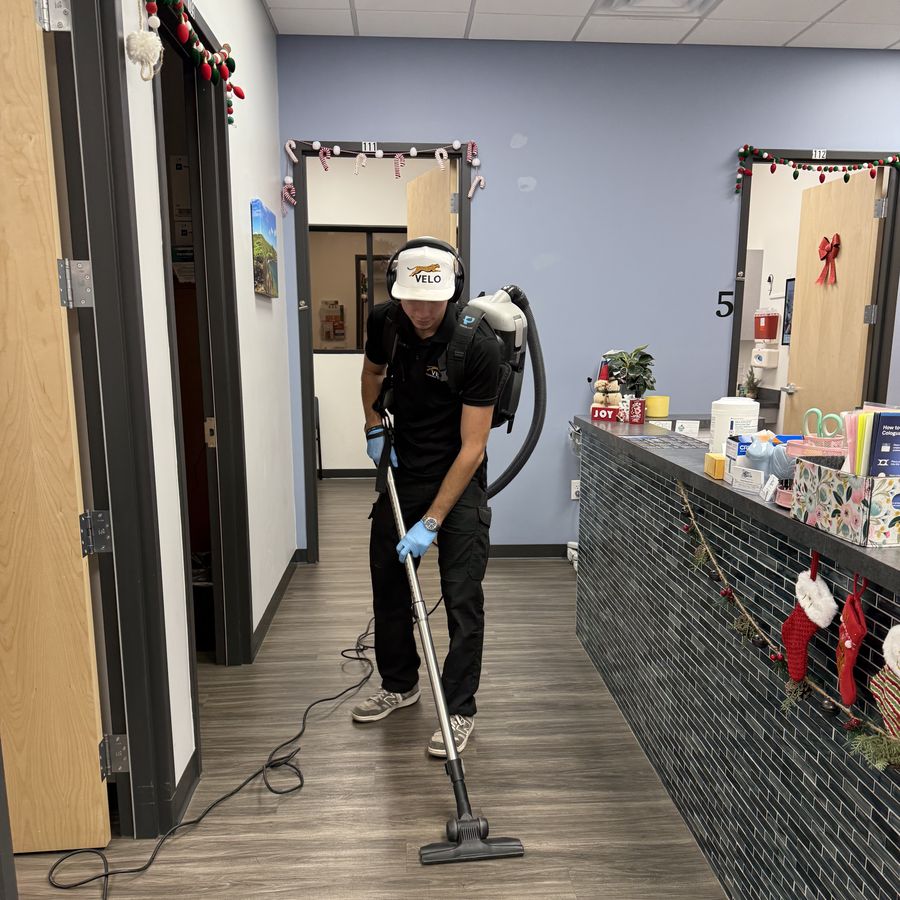 Velo Property Solutions team member in branded uniform performing office cleaning